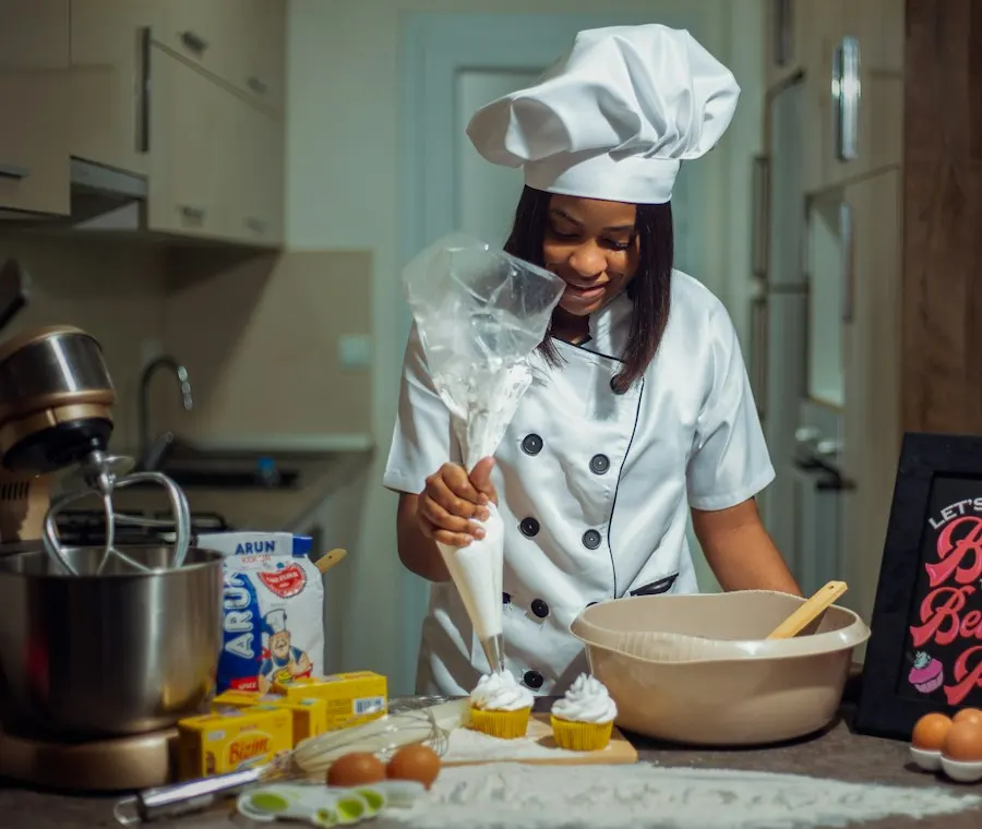 Smiling student baker in chef whites piping icing