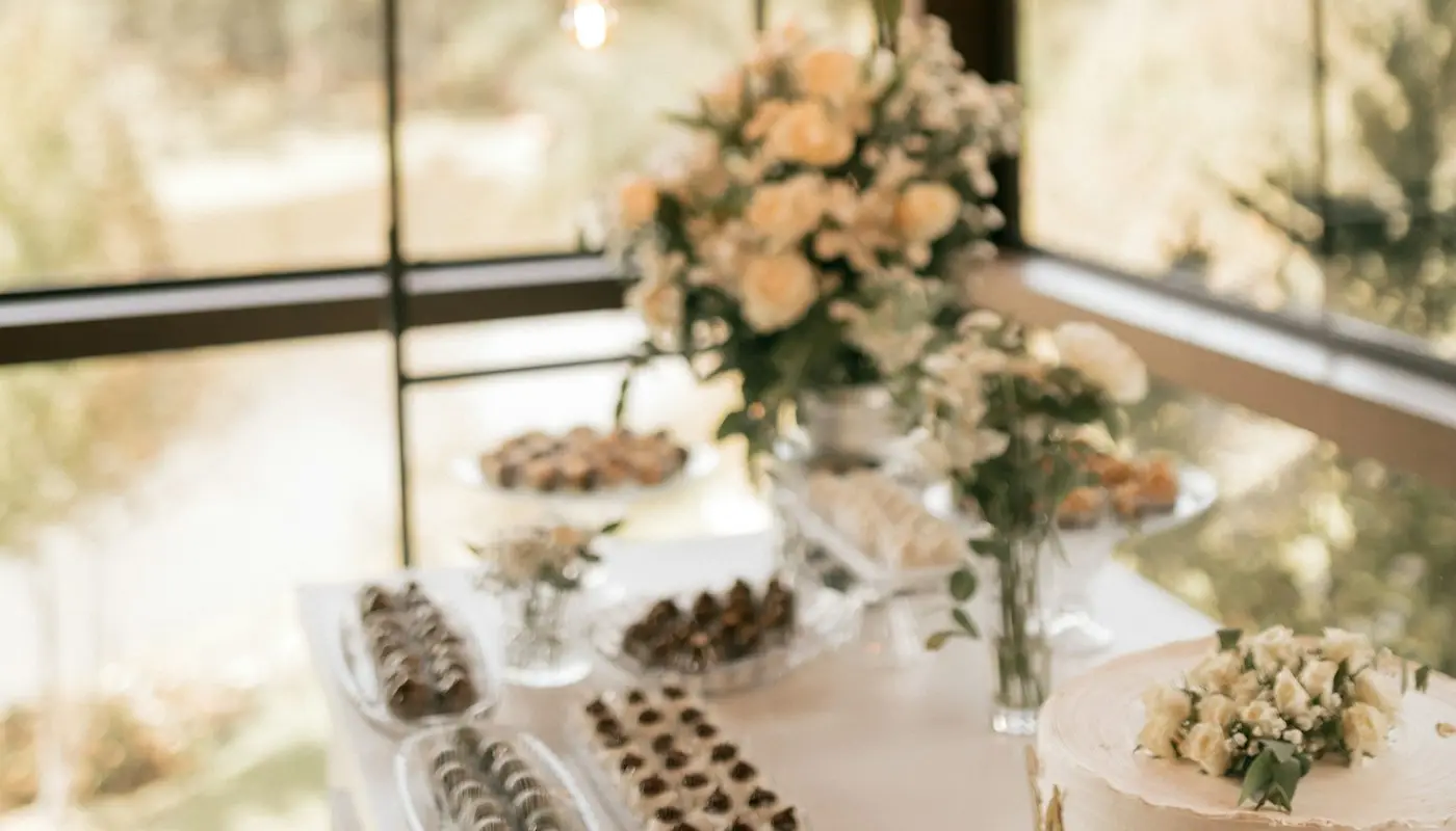Dessert table with cake, treats and floral arrangements
